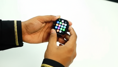 Person holding a small smartwatch with a blurred background